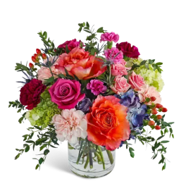 Mixed bouquet of roses, carnations, and hydrangeas in a clear glass vase