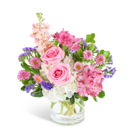 Pink roses and mixed blooms arranged in a clear glass vase
