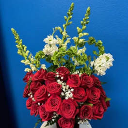 Arrangement of red roses with baby’s breath and tall white flowers in a black vase
