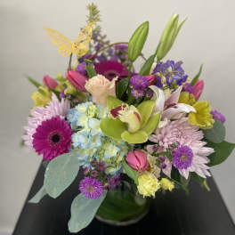 Colorful mixed bouquet in a glass vase with lilies, roses, and daisies