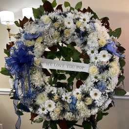 Large floral wreath with white and blue flowers and a ribbon banner