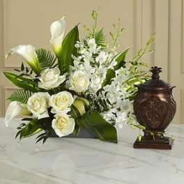 White roses and calla lilies arranged with white orchids in a dark vase