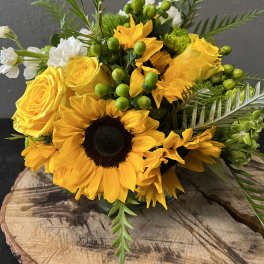 Yellow sunflowers and roses with green berries in a bouquet
