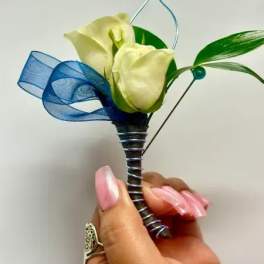 White calla lily boutonniere with blue ribbon and green leaves