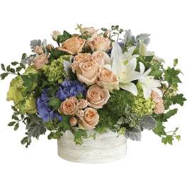Peach roses and white lilies in a low white container