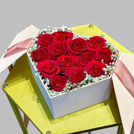 Box of red roses with pink ribbons on a gold stand