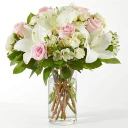 Pink roses and white lilies in a clear glass vase