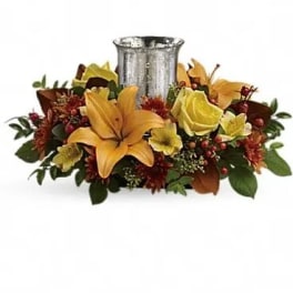 Floral centerpiece with lilies and roses around a silver vase