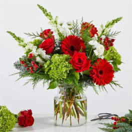 Red roses and gerbera daisies in a glass vase with white snapdragons