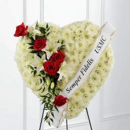 Heart-shaped floral tribute with red roses and white lilies on a stand