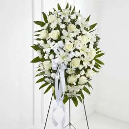 White floral standing spray on an easel with a ribbon