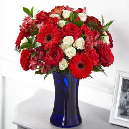 Red and white mixed bouquet in a blue glass vase
