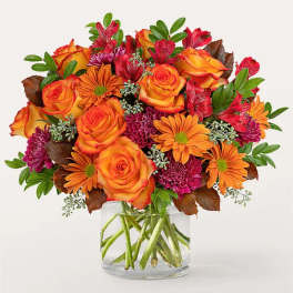 Orange roses and daisies in a clear glass vase