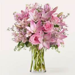 Pink lilies and roses arranged in a clear glass vase