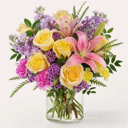 Bouquet of yellow roses and pink lilies in a clear glass vase