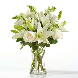 White lilies and roses arranged in a clear glass vase