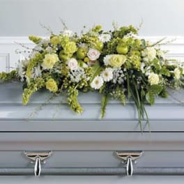 White and pale green floral casket spray on a gray casket