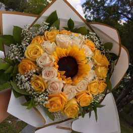 Bouquet of yellow and cream roses with a sunflower center