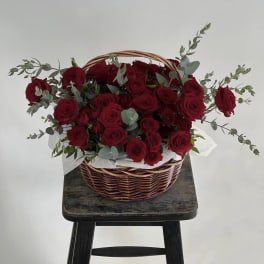 Basket of red roses with eucalyptus on a stool