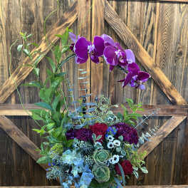 Purple orchids and mixed flowers in a blue vase