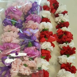 Bundles of pink, red, and white carnations tied with purple and red ribbons