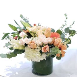 Peach and white flower arrangement in a dark green vase