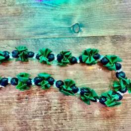 Green and dark blue beaded garland laid on a wooden surface