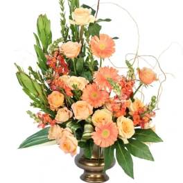 Peach roses and orange gerbera daisies in a gold vase