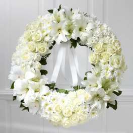 White floral wreath with roses and lilies and a ribbon bow