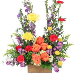 Colorful floral arrangement with roses, carnations, and purple filler flowers in a wooden box