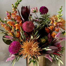 Colorful mixed flower arrangement in a gold vase