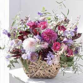Mixed pink and purple flowers in a woven basket
