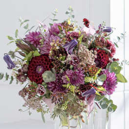 Bouquet of purple and burgundy flowers in a clear glass vase