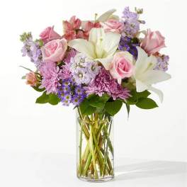 Pink roses and white lilies in a clear glass vase