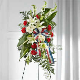 Standing floral spray with white lilies, red carnations, and ribbon