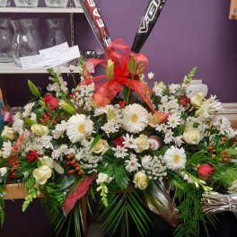Large floral arrangement with white daisies, roses, and red ribbon accents