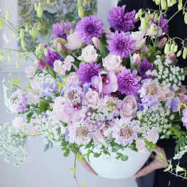 Large bouquet of purple and pale pink flowers in a white vase