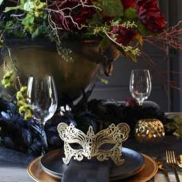 Dark floral centerpiece with red blooms in a gold bowl on a decorated table