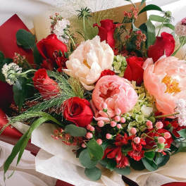 Bouquet of red and blush flowers wrapped in white paper