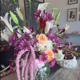 Mixed bouquet with lilies, roses, and purple daisies in a glass vase