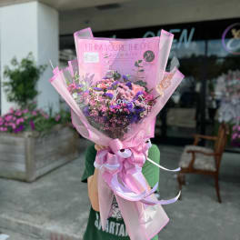 Pink and purple bouquet wrapped in pink paper with a ribbon bow