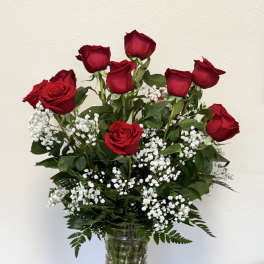 Red roses arranged in a clear glass vase with white baby's breath