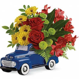 Bouquet of red roses and yellow daisies in a blue toy truck