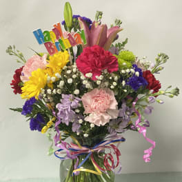 Colorful birthday bouquet in a glass vase with a "Happy Birthday" topper
