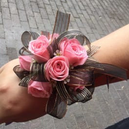 Pink rose wrist corsage with dark ribbon loops