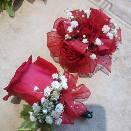 Two small red rose bouquets with white filler flowers and ribbon bows