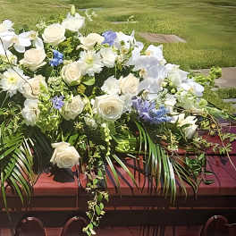 Large white floral casket spray with blue accents