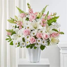 Pink roses and white lilies arranged in a white vase