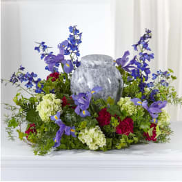 Purple and blue floral arrangement around a gray urn