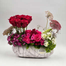 Pink and red roses arranged in a white marble-patterned vase